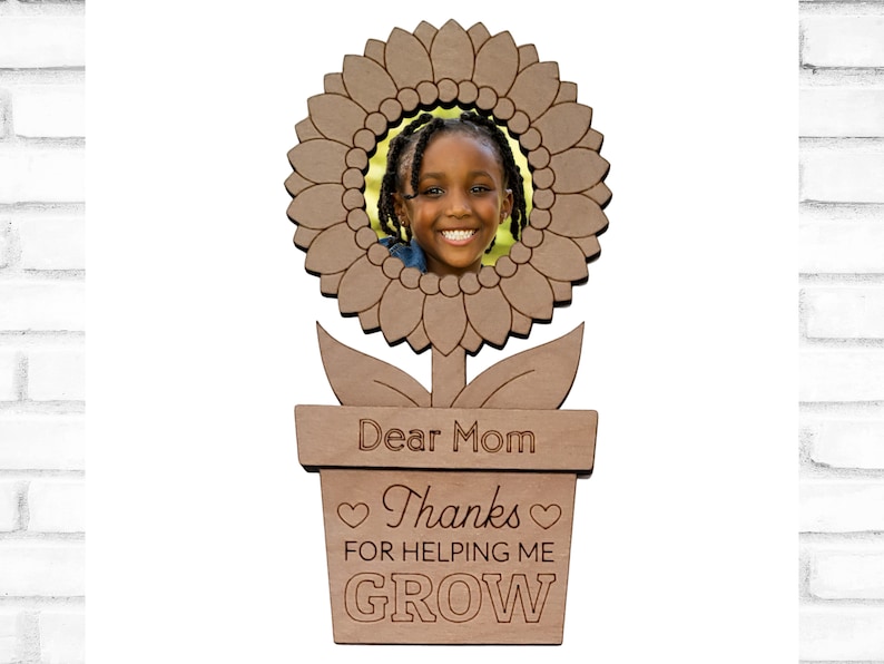 May include: A wooden sunflower photo frame with a brown pot and the text "Dear Mom Thanks for helping me GROW" in a white background.
