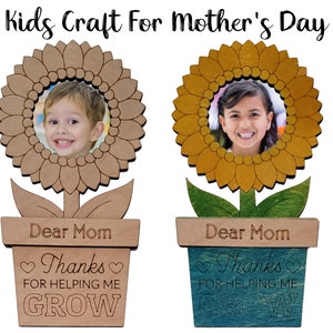 May include: Two wooden sunflower photo frames with a child's photo in each. The frames are painted in brown and yellow with green leaves and a pot with the text "Dear Mom Thanks for helping me GROW".