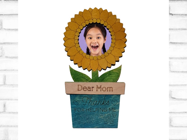 May include: A wooden sunflower photo frame with a blue and green pot. The pot has the text "Dear Mom Thanks for helping me grow" on it.