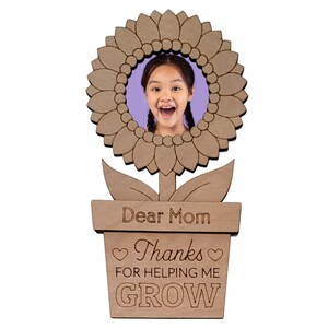 May include: Wooden photo frame shaped like a sunflower with a pot and the text "Dear Mom Thanks for helping me GROW".
