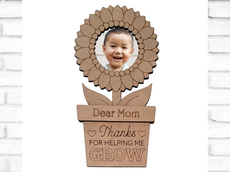 May include: Wooden photo frame shaped like a sunflower with a pot and the text "Dear Mom Thanks for helping me GROW".