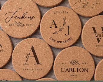 May include: A collection of round, light brown cork coasters featuring various laser-engraved designs, including family names like Jenkins, Williams, and Carlton, initials, dates such as 2024, and botanical illustrations of leaves and hands.