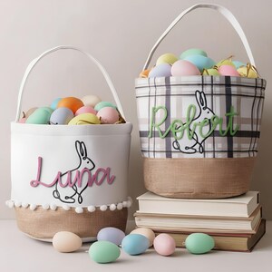 Two Easter baskets filled with pastel-colored eggs sit on a stack of books, with the baskets decorated with the names "Luna" and "Rebeat".