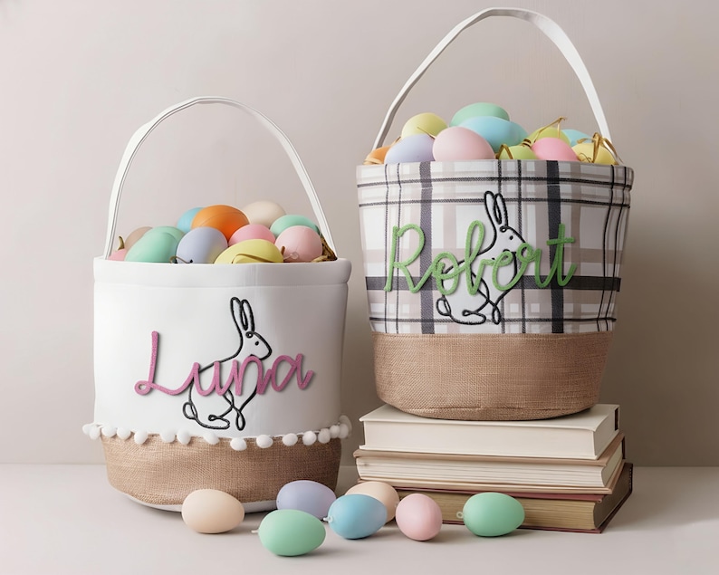 Two Easter baskets filled with pastel-colored eggs sit on a stack of books, with the baskets decorated with the names "Luna" and "Rebeat".
