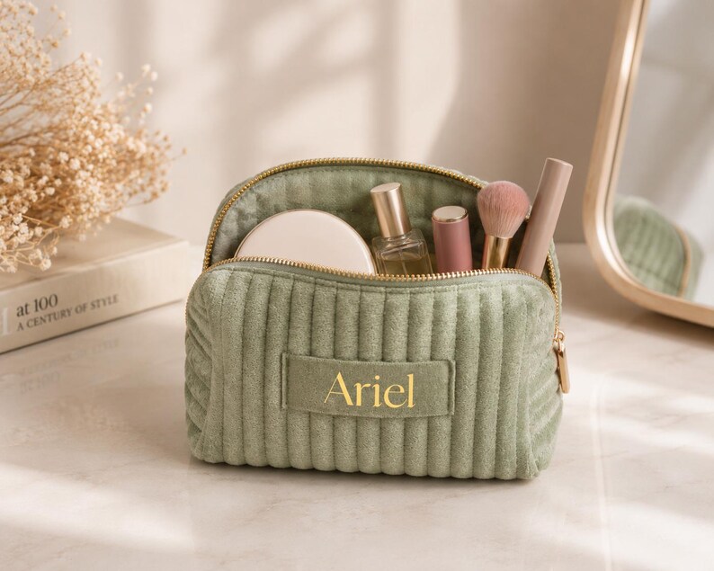A green makeup bag with the name "Ariel" printed on it, containing various makeup items such as a compact, powder, and a brush.