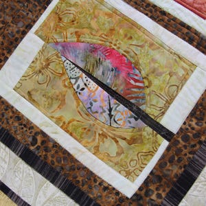 K&ouml;nnte beinhalten: Nahaufnahme eines handgefertigten Quilts mit einem Blattdesign. Der Quilt zeigt eine Kombination aus gemusterten Stoffen in Braun-, Beige- und Wei&szlig;t&ouml;nen. Das zentrale Design umfasst eine farbenfrohe Blattform mit rosa, lila und wei&szlig;en Akzenten.