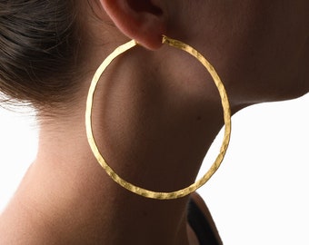 May include: Large gold hoop earrings with a hammered texture.