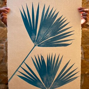 May include: Two teal blue palm leaves printed on a beige textured paper background.