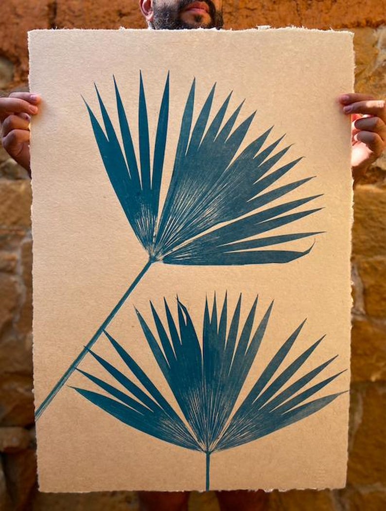 May include: Two teal blue palm leaves printed on a beige textured paper background.