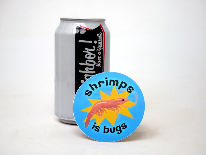 Puede incluir: Una pegatina redonda azul y amarilla con una ilustraci&oacute;n de camar&oacute;n y el texto "shrimps is bugs".