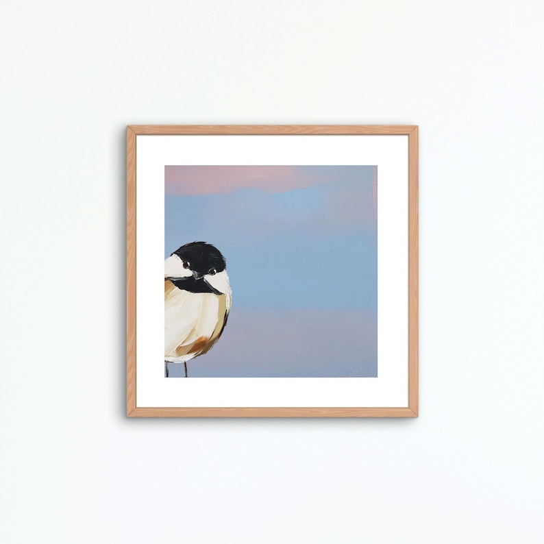 May include: A framed painting of a bird with a black head and white chest, perched on a branch against a blue and pink background.