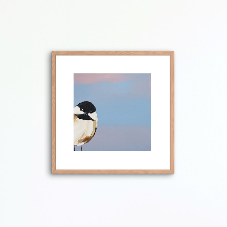 Puede incluir: Una pintura enmarcada de un p&aacute;jaro peque&ntilde;o con cabeza negra y pecho blanco, posado sobre un fondo suave azul y rosa.