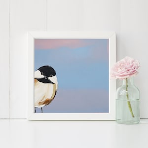 Puede incluir: Una pintura enmarcada de un p&aacute;jaro peque&ntilde;o con marcas blancas y negras sobre un fondo azul claro con un degradado rosa y morado en la parte superior.