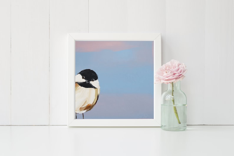 Puede incluir: Una pintura enmarcada de un p&aacute;jaro peque&ntilde;o con marcas blancas y negras sobre un fondo azul claro con un degradado rosa y morado en la parte superior.