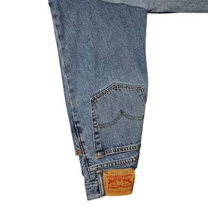 May include: Light blue denim jeans with a classic five-pocket design. The jeans feature a back pocket and a red and white Levi Strauss & Co. label. The waist size is W 34 and the length is L 32.