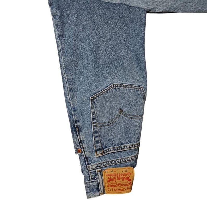 May include: Light blue denim jeans with a classic five-pocket design. The jeans feature a back pocket and a red and white Levi Strauss & Co. label. The waist size is W 34 and the length is L 32.