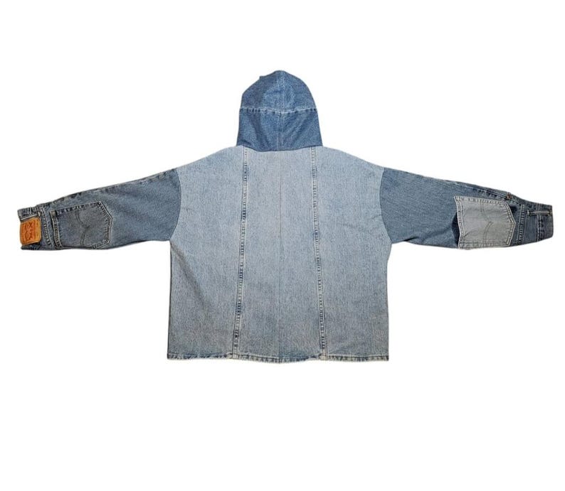 May include: A light and medium blue denim jacket with a hood. The jacket features a patchwork design with different shades of denim. The sleeves have pockets and a brown leather patch. A casual outerwear garment.
