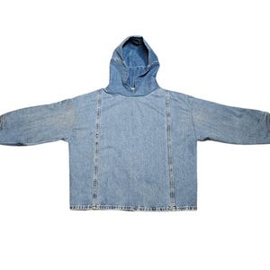 May include: A light blue denim hoodie with a hood and long sleeves. The jacket has a relaxed fit and features vertical seams down the front and back. The cuffs have button details.