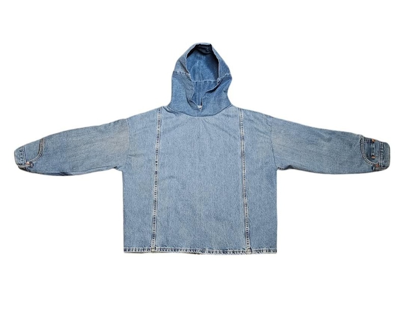 May include: A light blue denim hoodie with a hood and long sleeves. The jacket has a relaxed fit and features vertical seams down the front and back. The cuffs have button details.