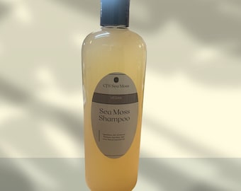 May include: A clear plastic bottle of Sea Moss Shampoo with a black cap. The bottle has a brown label with the text "CFS Sea Moss", "Vegan", and "Sea Moss Shampoo". The label also includes a list of ingredients.