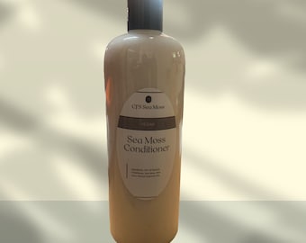 May include: A large, white plastic bottle of Sea Moss Conditioner. The bottle has a black cap and a label with the words "Sea Moss Conditioner" and "Vegan" printed on it.