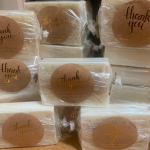 May include: A stack of white soap bars wrapped in clear plastic with brown paper thank you stickers. The stickers say "Thank you for supporting my small business".