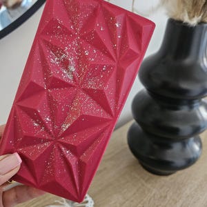 May include: A red chocolate bar with a geometric design and a sparkly finish.