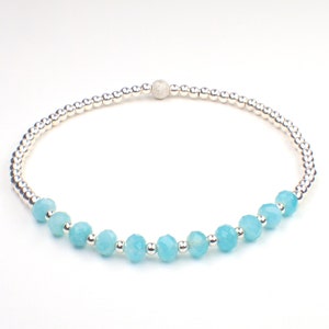 May include: A delicate bracelet with a silver chain and light blue gemstone beads.