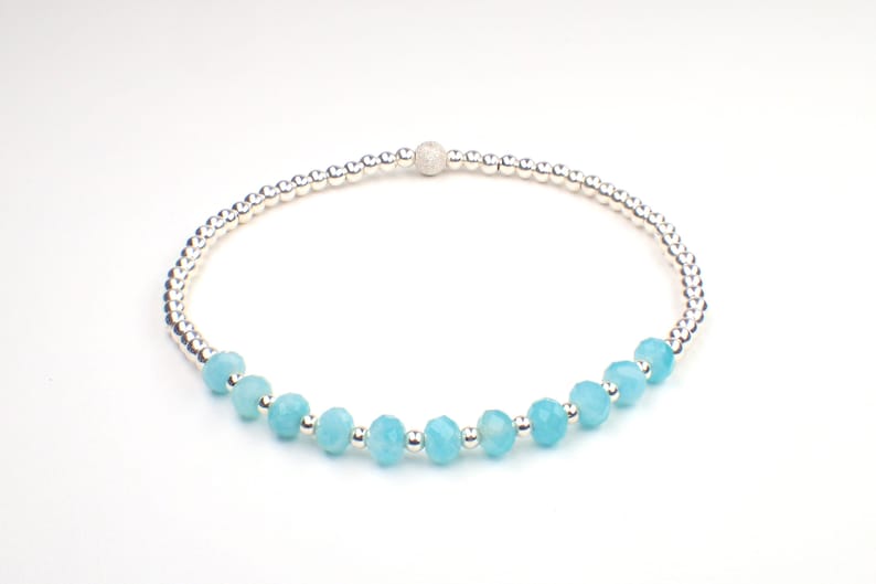 May include: A delicate bracelet with a silver chain and light blue gemstone beads.