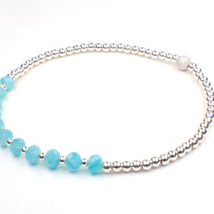May include: A silver beaded bracelet with a textured silver bead and a row of light blue faceted beads.
