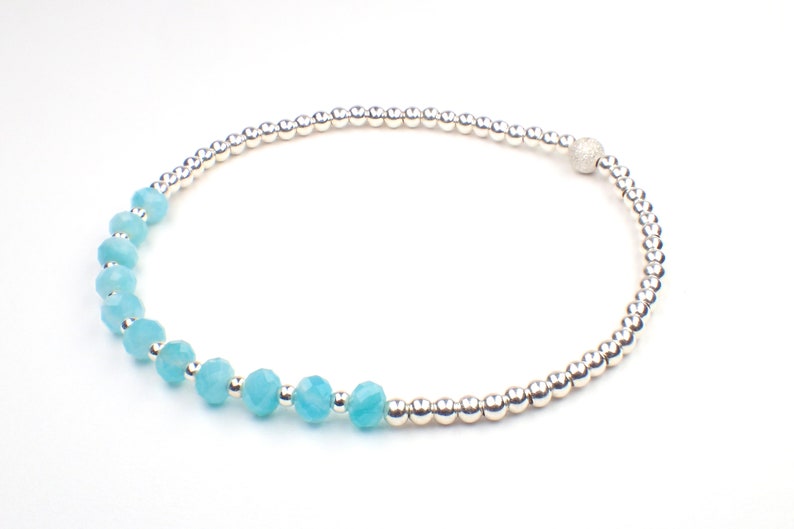 May include: A silver beaded bracelet with a textured silver bead and a row of light blue faceted beads.