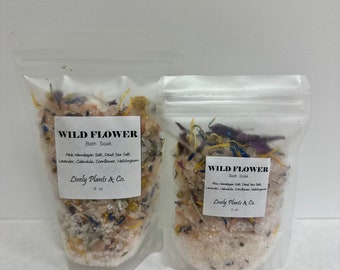May include: Two clear plastic bags filled with bath salts and dried flowers. The bags are labeled "WILD FLOWER Bath Soak" and list the ingredients: Pink Himalayan Salt, Dead Sea Salt, Lavender, Calendula, Cornflower, Helichrysum. The bags are labeled "Lively Plants & Co." and list the size as 8 oz.