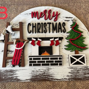 Peut inclure: Une pancarte en bois blanc avec une cheminée rouge et noire, une échelle, un traîneau, deux patins à glace et un sapin de Noël vert avec des décorations rouges. La pancarte indique "merry christmas" en lettres noires et rouges.