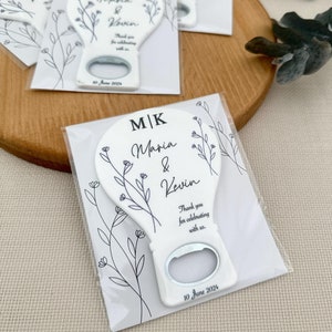 Puede incluir: Abrebotellas de cerámica blanca con un diseño floral y el texto "M/K Maria & Kevin Gracias por celebrar con nosotros. 10 de junio de 2024"