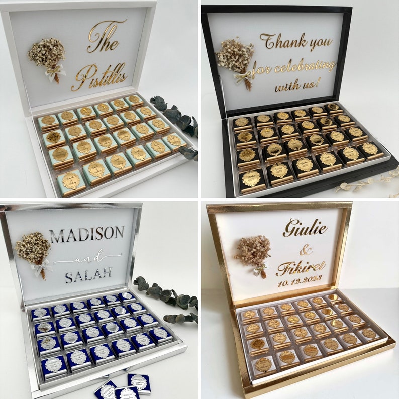 K&ouml;nnte beinhalten: Vier wei&szlig;e Boxen mit goldenen Schriftz&uuml;gen und einem kleinen Strau&szlig; wei&szlig;er Blumen auf dem Deckel. Jede Box enth&auml;lt 36 kleine Schokoladenquadrate mit goldenen Folienverpackungen. Die Boxen sind mit "The Pistills", "Vielen Dank f&uuml;rs Feiern mit uns!", "Madison und Salah" und "Giulie & Fikiret 10.12.2038" beschriftet.