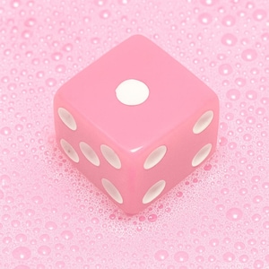 May include: A pink die with white dots, showing the number one on the top face. The die is set against a pink background with a bubbly texture. The dice is a classic game piece.