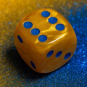 May include: A golden-yellow die with blue dots, set against a shimmering blue and gold background. The six-sided die is a classic game piece, perfect for board games, dice games, and other forms of entertainment.