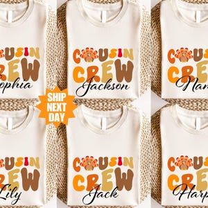 Pode incluir: Seis camisetas creme com as palavras "COUSIN CREW" em letras laranja, marrom e amarelo. Cada camisa tem um nome diferente em fonte cursiva: Sophia, Jackson, Name, Lily, Jack e Harper. Um gráfico de peru está acima da palavra "CREW".