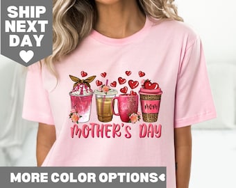 Pode incluir: Camiseta rosa com um gráfico de três xícaras de café com corações e o texto "Dia das Mães".
