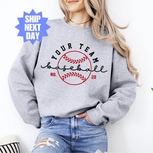 Può includere: Felpa grigia con una grafica di baseball nera e rossa e il testo "Your Team Baseball No. 28".