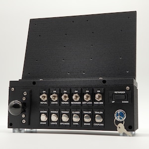 Puede incluir: Panel de control negro con múltiples interruptores y botones etiquetados para diversas funciones del vehículo, incluyendo luces, limpiaparabrisas y frenos. Cuenta con una llave y un botón negro. El panel está montado sobre una superficie clara.