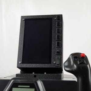 Peut inclure: Un cockpit de simulateur de vol noir avec un petit écran et un joystick avec un bouton rouge. L'écran est noir et est monté sur un support noir. Le joystick a une poignée noire et une base noire.