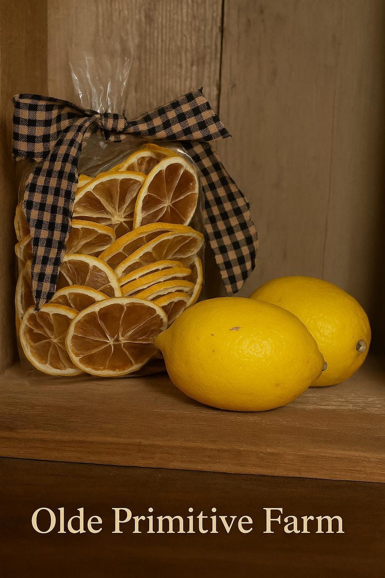 May include: A clear bag filled with dried lemon slices, tied with a black and tan checkered bow, and two fresh yellow lemons. The text "Olde Primitive Farm" is at the bottom.