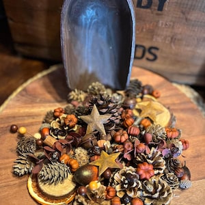May include: A wooden bowl filled with a variety of fall-themed potpourri, including pinecones, mini pumpkins, cinnamon sticks, dried orange slices, and star-shaped accents.