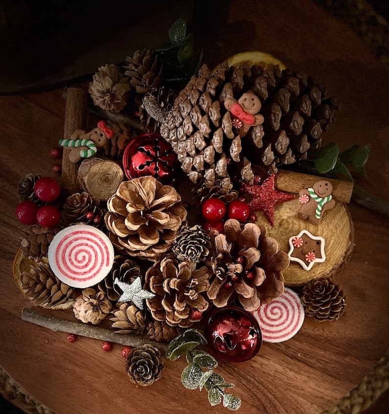 May include: A festive Christmas arrangement featuring pine cones, cinnamon sticks, red berries, and gingerbread men. The arrangement is decorated with red and white candy canes and a silver star.
