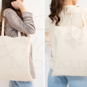 May include: Two people are holding a blank canvas tote bag. The bag is made of natural cotton and has long handles. The bag is a great way to carry your essentials and show off your style.