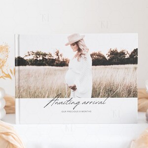 May include: A white photo album with a photo of a pregnant woman in a field. The text on the album reads "Awaiting arrival our precious 9 months".