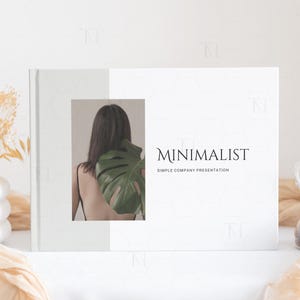 May include: A white presentation folder with a simple design. The front cover features a photo of a person with a large green leaf behind them. The text "MINIMALIST" and "SIMPLE COMPANY PRESENTATION" is printed in black on the cover.