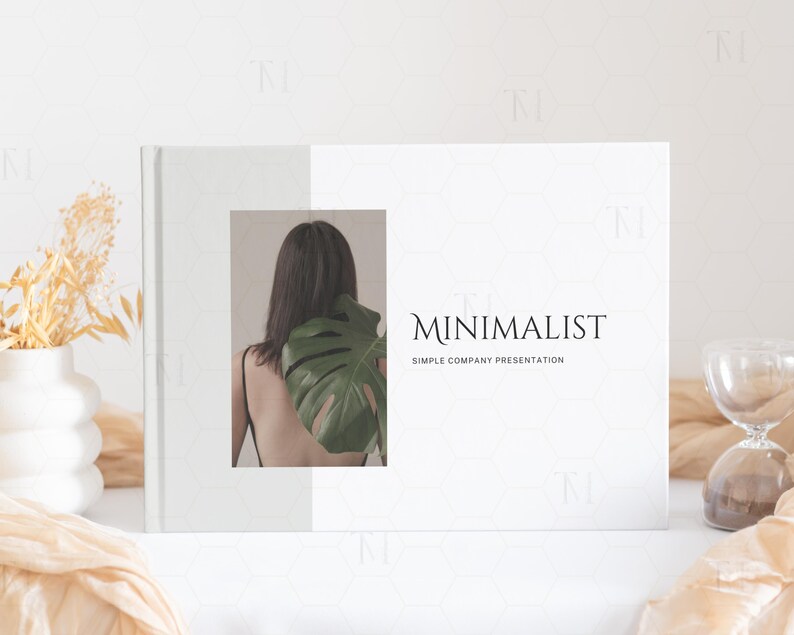 May include: A white presentation folder with a simple design. The front cover features a photo of a person with a large green leaf behind them. The text "MINIMALIST" and "SIMPLE COMPANY PRESENTATION" is printed in black on the cover.
