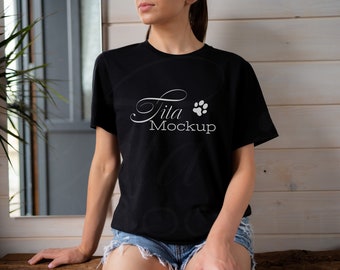May include: A black t-shirt with a white paw print and the text "Tila Mockup" on the front. The shirt is being worn by a person with long brown hair.